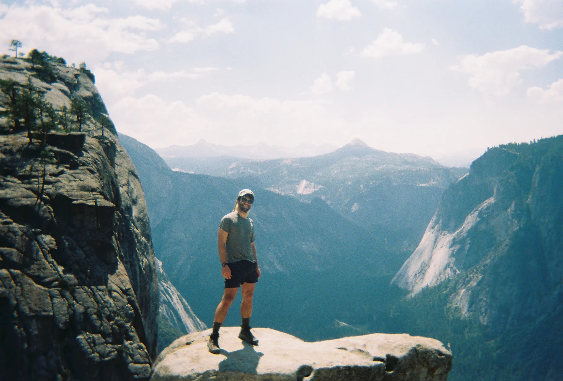 Dylan at Yosemite, standing on a cliff with mountain views